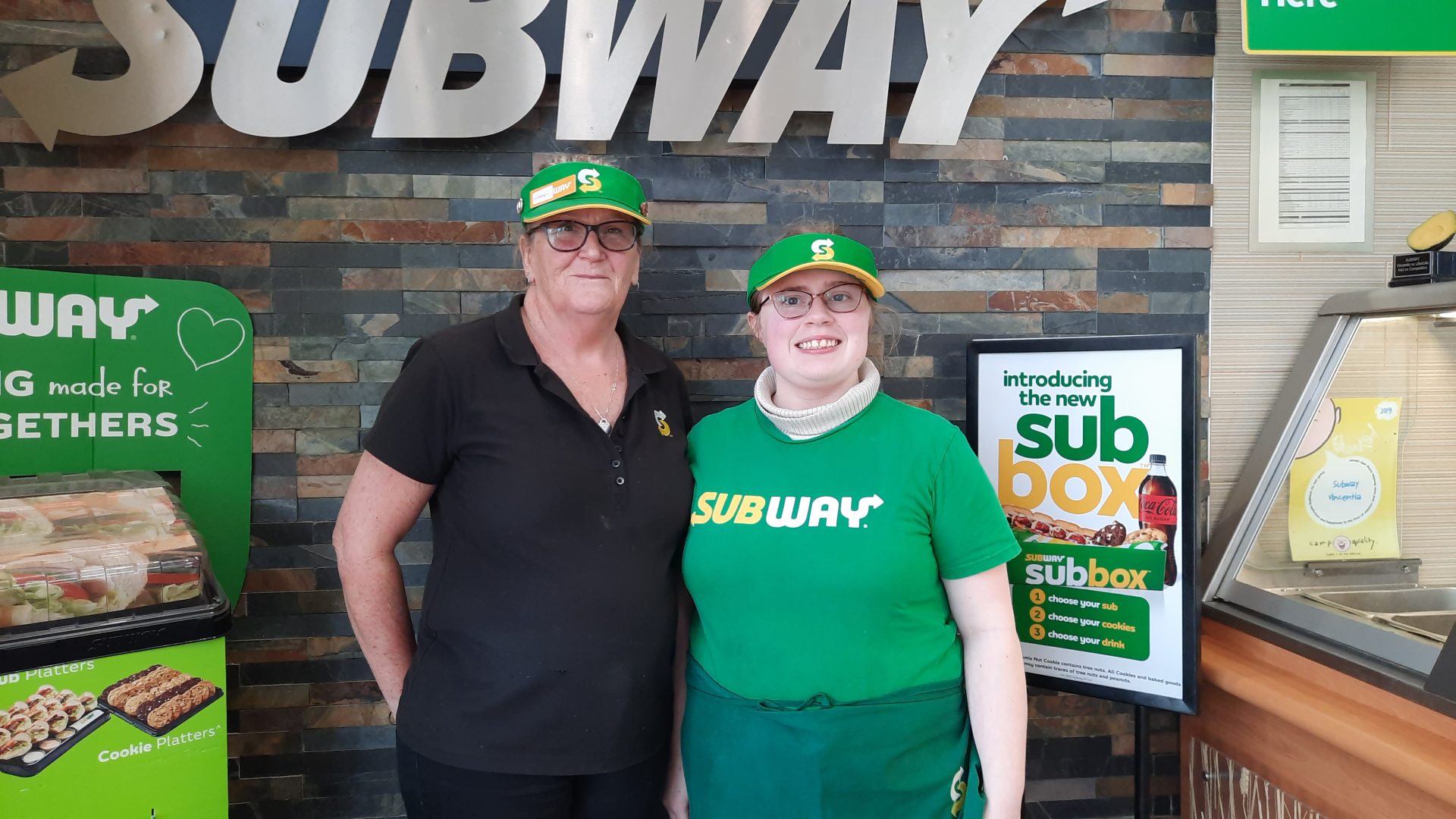Two smiling employees wearing uniforms and hats, with one supported by tpg in terms of employment